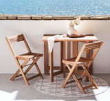 Balkon-Set aus Holz mit zwei Klappstühlen und einem Tisch, auf einem Balkon mit Meerblick, aus seitlicher Perspektive fotografiert.
