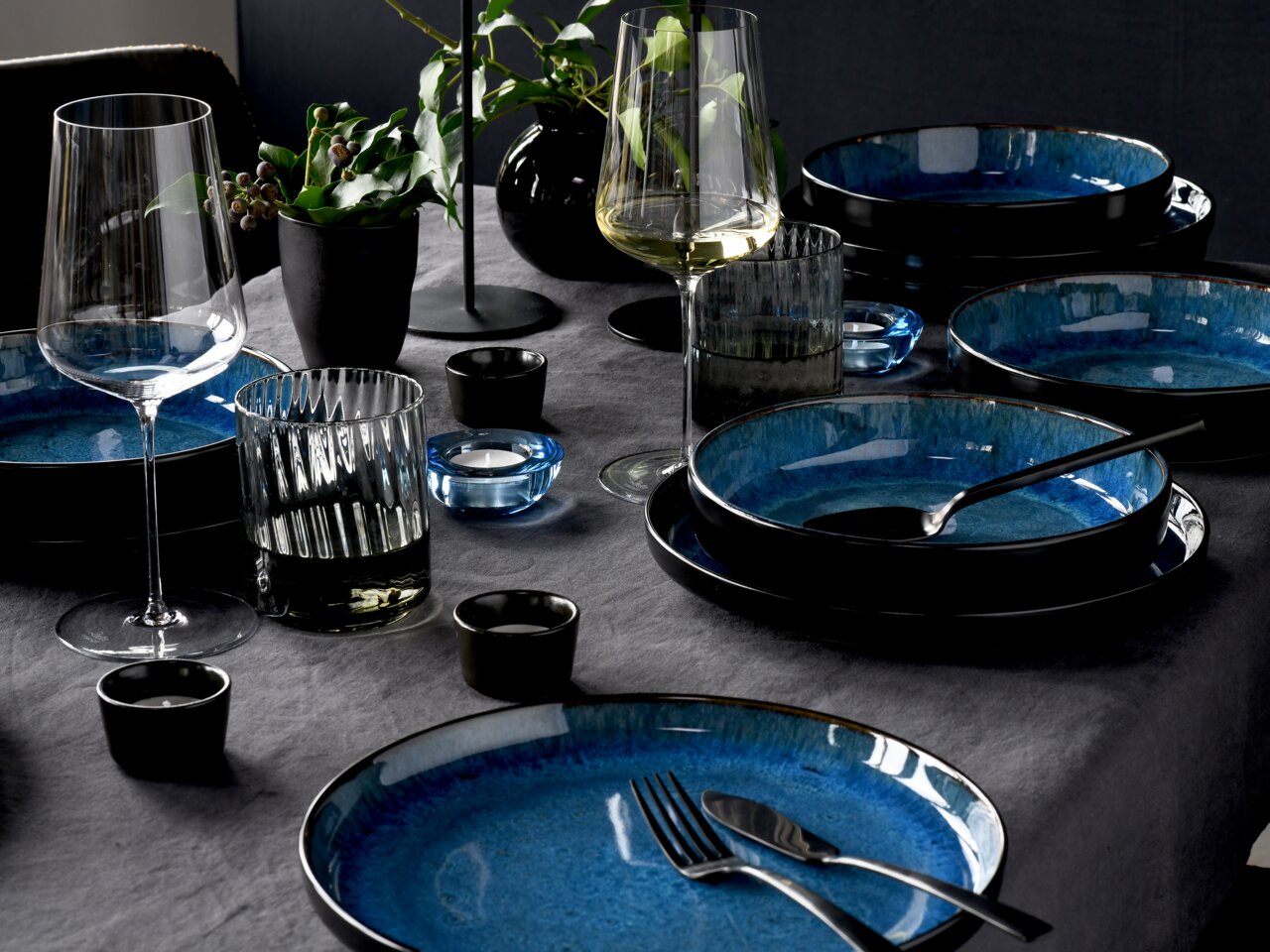 Elegantes Tafelservice 12-tlg in Blau und Schwarz, von schräg oben fotografiert, mit Gläsern und Dekoration auf einem gedeckten Tisch.