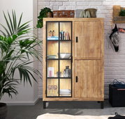Rustiek houten hoogkast met glazen deuren, versierd met boeken en serviesgoed, in een moderne woonkamer. Vooraanzicht.