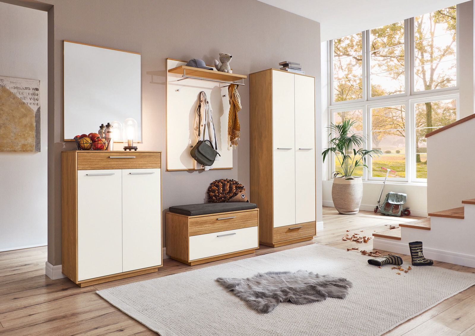 VOSS Dielenschrank LOVENO Moderne Garderobeneinrichtung mit Holz- und Weißakzenten, bestehend aus Schuhschrank, Sitzbank, Garderobenpaneel und Spiegel, in einem hellen Raum mit Blick auf große Fenster.