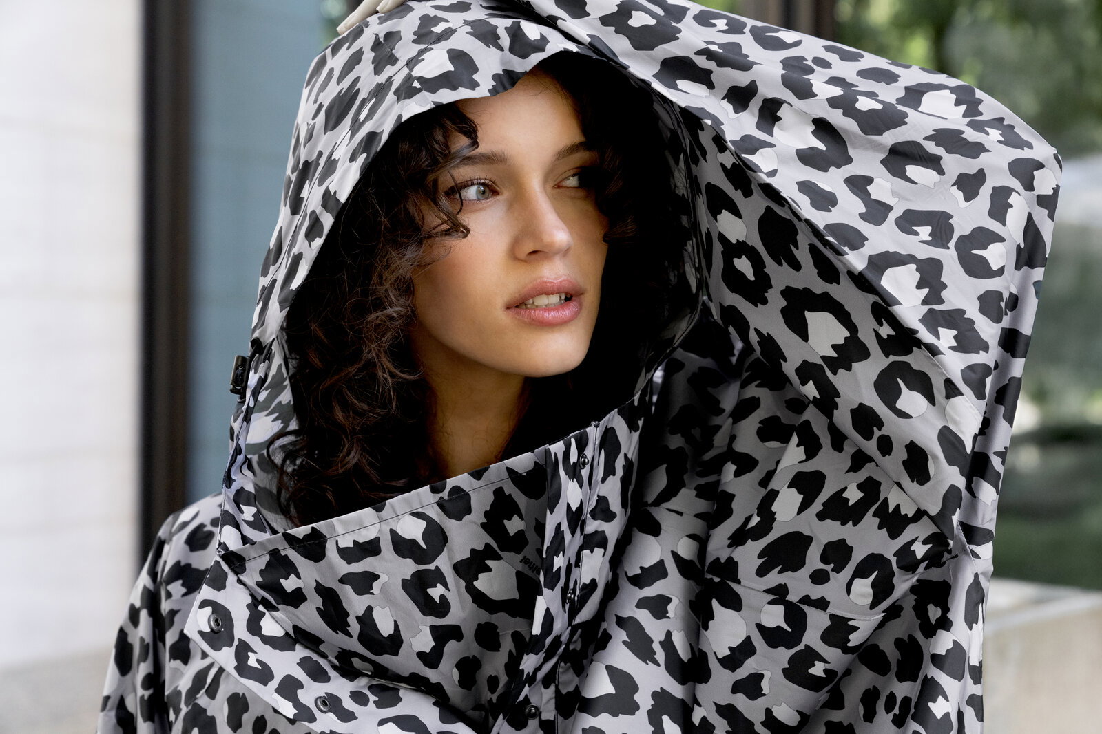 Nahaufnahme in 3/4-Ansicht: Model trägt eine schwarz-weiß gemusterte, voluminöse Kapuzenjacke mit Leopardenprint und blickt seitlich nach rechts.