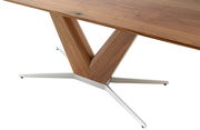Nahaufnahme eines Esstisches mit einer Tischplatte aus Holz und einem modernen, V-förmigen Tischbein aus Holz und Metall, seitliche Perspektive.