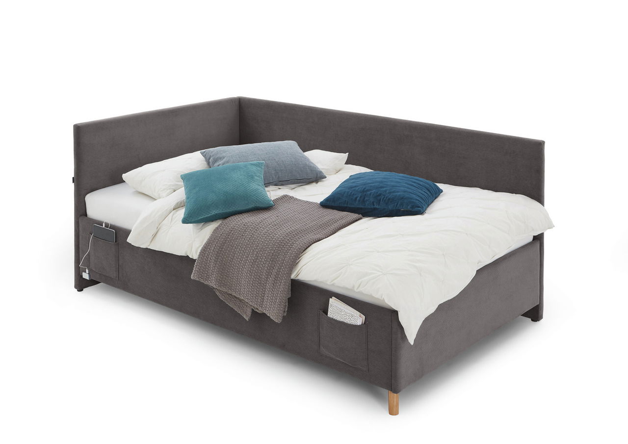 Polsterliege in grauem Stoff mit Kissen und Decke, seitliche Perspektive