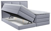 Lichtgrijs gestoffeerd boxspringbed met hoog hoofdbord, comfortabele topper en omhooggeklapte bedbodem met ruime opbergruimte, vanuit schuin vooraanzicht