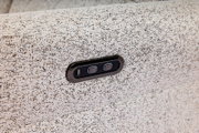 Close-up van een lichtgrijze stoffen bank met ingebouwde USB-oplaadaansluiting en twee knoppen, gezien vanaf de zijkant.
