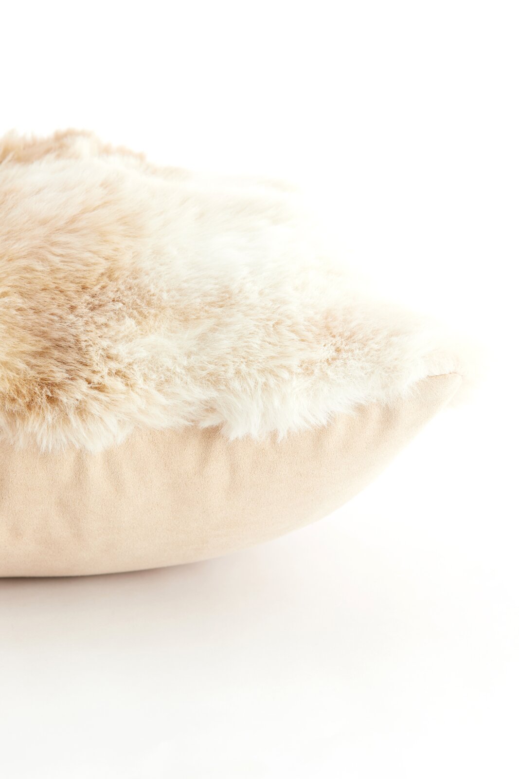 Close-up van een zacht, beige kussen met een donzig, crèmekleurig oppervlak, gezien vanaf de zijkant