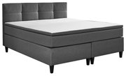 Graues Boxspringbett mit gepolstertem Kopfteil, seitliche Perspektive