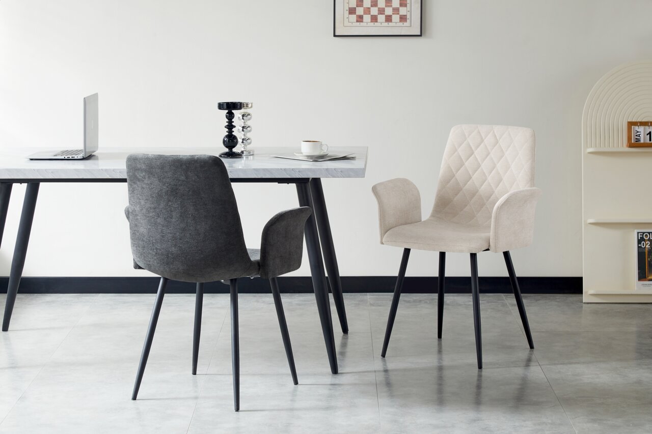 Zwei Armlehnstühle in einem modernen Esszimmer, einer in Grau und einer in Beige, mit schwarzem Metallgestell, seitliche Perspektive.
