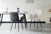 Twee stoelen met armleuningen in een moderne eetkamer, één in grijs en één in beige, met een zwart metalen frame, gezien vanaf de zijkant.