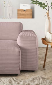 Nahaufnahme einer modernen, pastellfarbenen Sofaecke mit geripptem Stoffbezug, im Hintergrund ein minimalistisches Dekor mit Pflanzen und einer Holzablage.