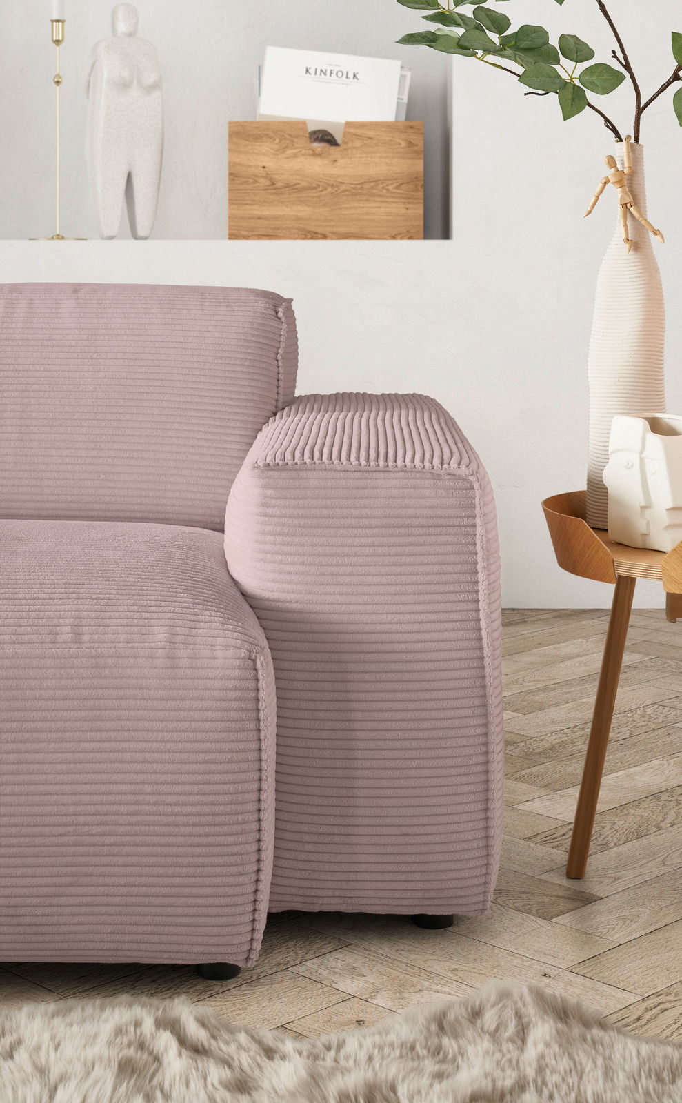 Nahaufnahme einer modernen, pastellfarbenen Sofaecke mit geripptem Stoffbezug, im Hintergrund ein minimalistisches Dekor mit Pflanzen und einer Holzablage.