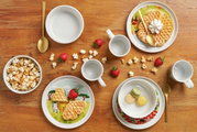 Vogelperspectief op een kinderservies met bouwplaatsmotief, bestaande uit borden, kommen en kopjes, versierd met wafels, popcorn en aardbeien.