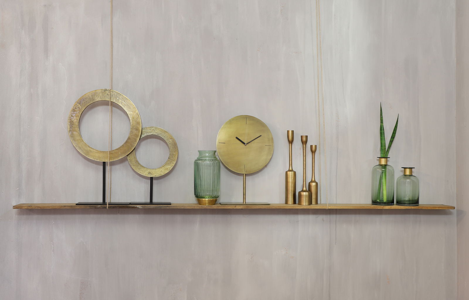 Dekoratives Arrangement mit goldenen Ringen, Uhr und Vasen auf einem Regal, seitliche Perspektive