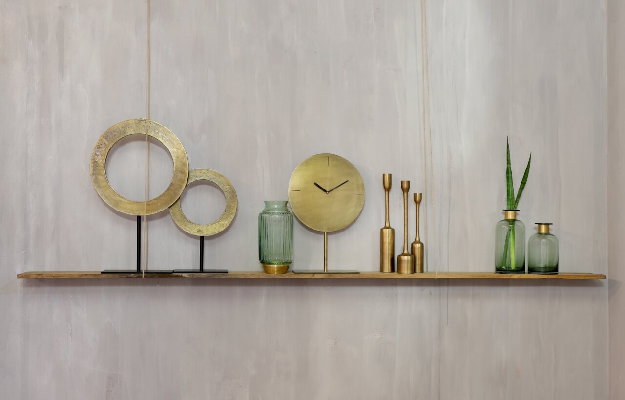 Dekoratives Arrangement mit goldenen Ringen, Uhr und Vasen auf einem Regal, seitliche Perspektive