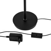 Schwarzer runder Lampenfuß einer Stehleuchte mit Stange, Kabel, Inline-Schalter und Netzteil, freigestellt auf weißem Hintergrund, Ansicht schräg von oben