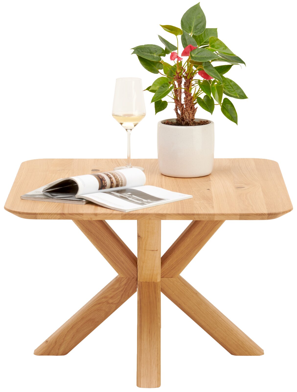 Moderner Beistelltisch aus Holz mit X-förmigen Beinen, darauf eine Pflanze, ein Weinglas und ein aufgeschlagenes Magazin, aus frontaler Perspektive.