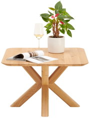 Moderne houten bijzettafel met X-vormige poten, met daarop een plant, een wijnglas en een opengebladerd tijdschrift, gezien van voren.