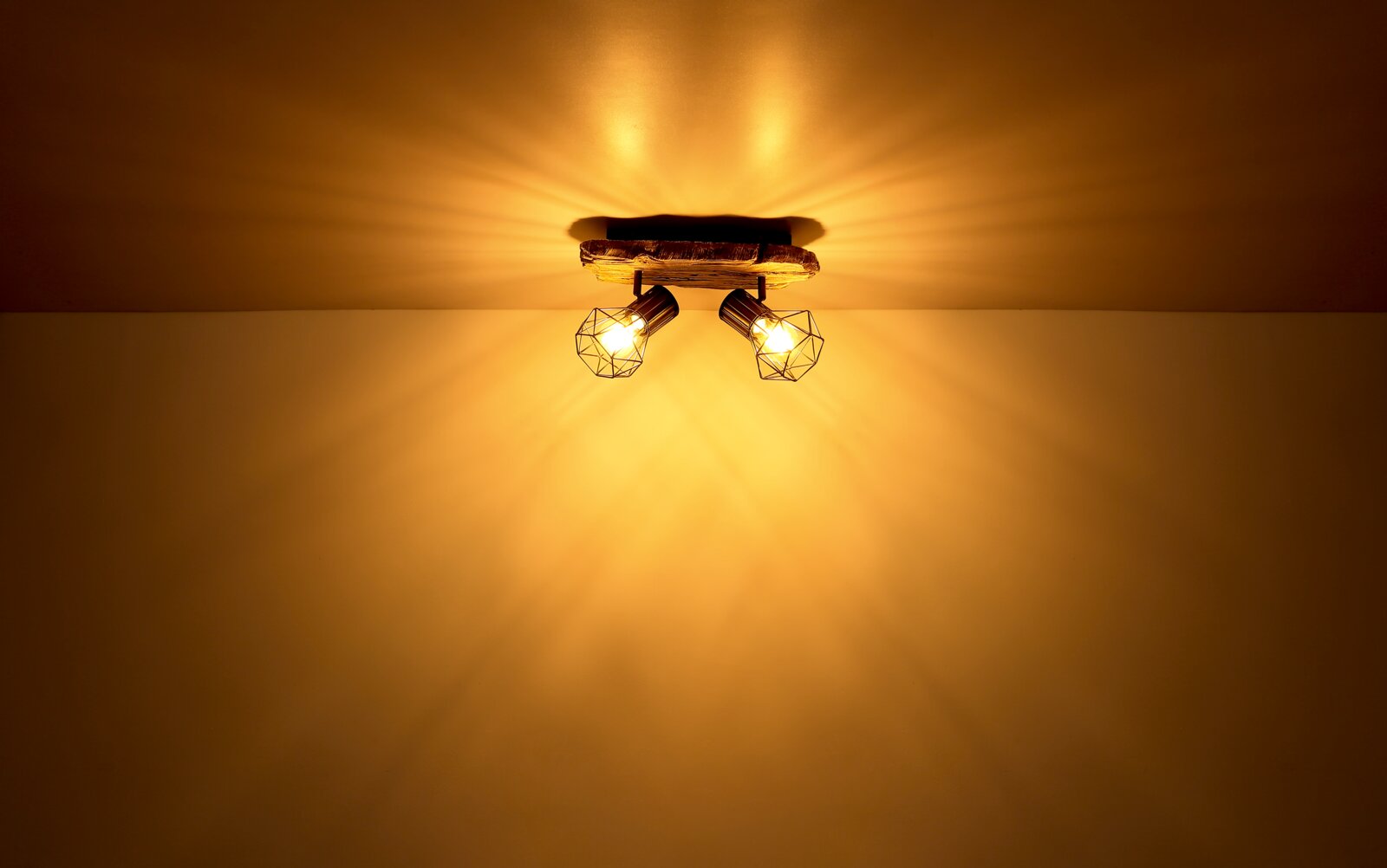 Deckenstrahler mit zwei leuchtenden Lampen in geometrischen Käfigen, von unten betrachtet.