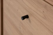 Nahaufnahme eines schwarzen Griffs auf einer Holzschublade, seitliche Perspektive