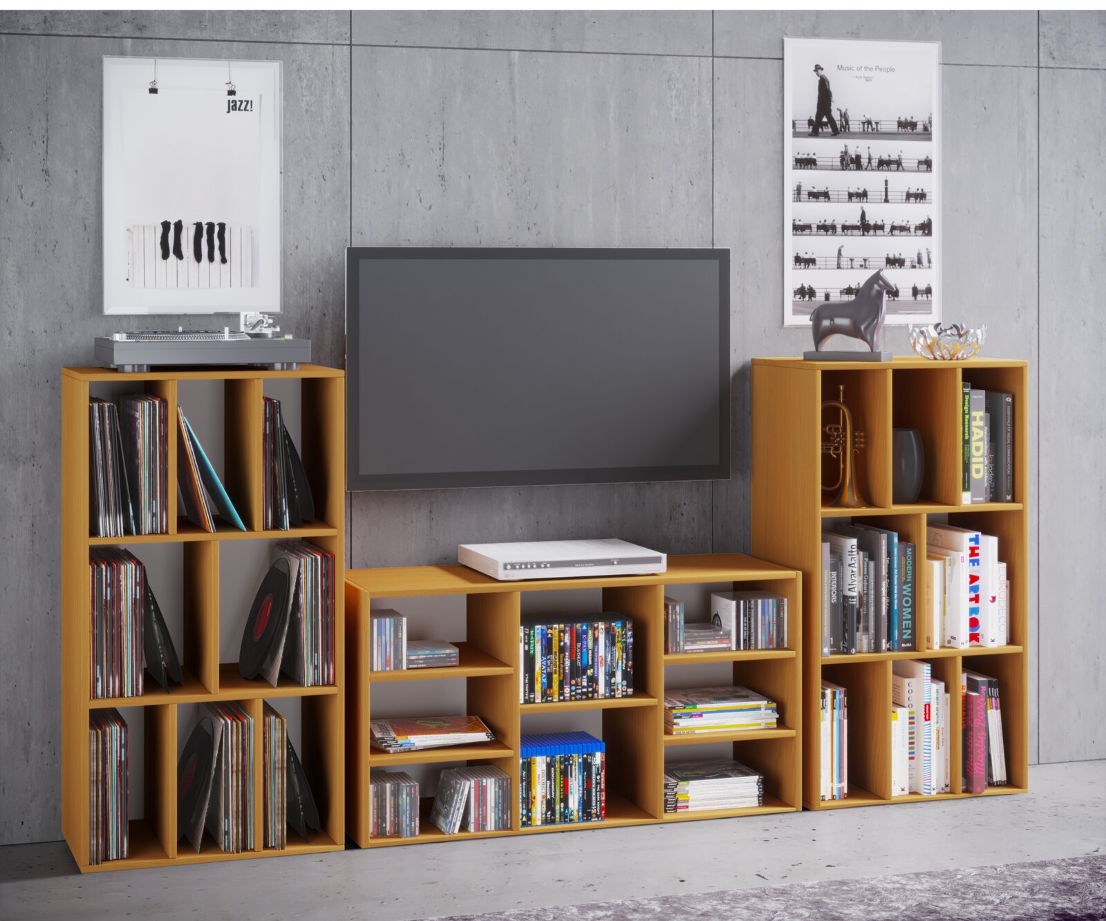 Frontale Ansicht einer modularen Wohnwand aus hellen Holzregalen mit Fächern für Schallplatten, Bücher und DVDs, mit TV in der Mitte und Plattenspieler oben links vor grauer Betonwand.