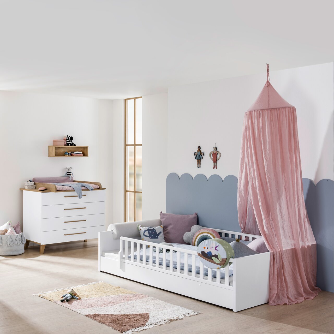 Kinderzimmer mit weißem Bodenbett, Rausfallschutz und rosa Baldachin, seitliche Perspektive