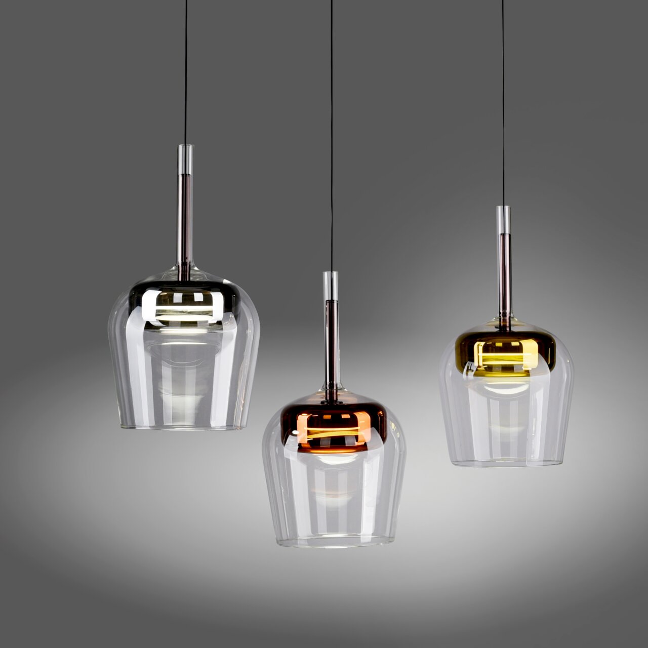 Drie moderne Q-KON-hanglampen in verschillende kleuren, van links naar rechts: transparant, koperkleurig en goudkleurig, gezien van voren.