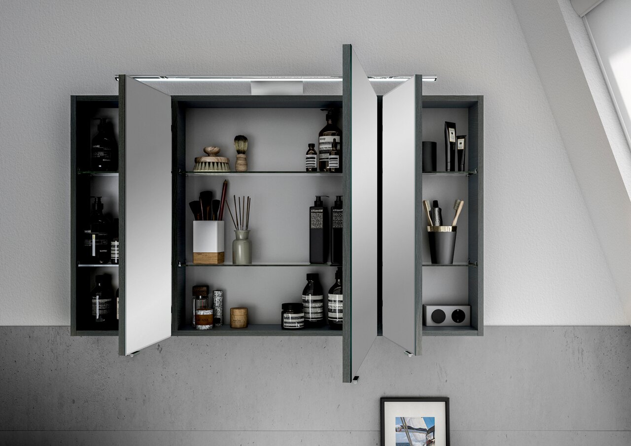 Moderner Spiegelschrank mit geöffneten Türen, gefüllt mit Pflegeprodukten und Accessoires, aus der Frontalperspektive betrachtet.