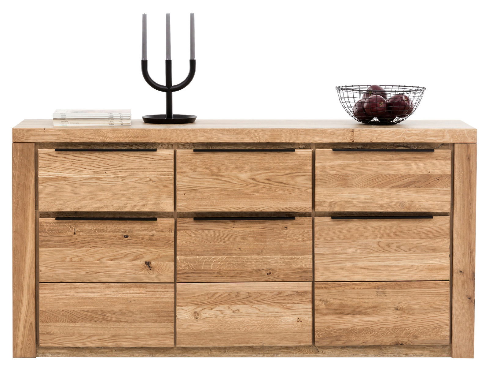 Frontale Ansicht eines modernen Sideboards aus Holz mit sechs Schubladen, dekoriert mit einem schwarzen Kerzenhalter, einem Stapel Bücher und einem Obstkorb.