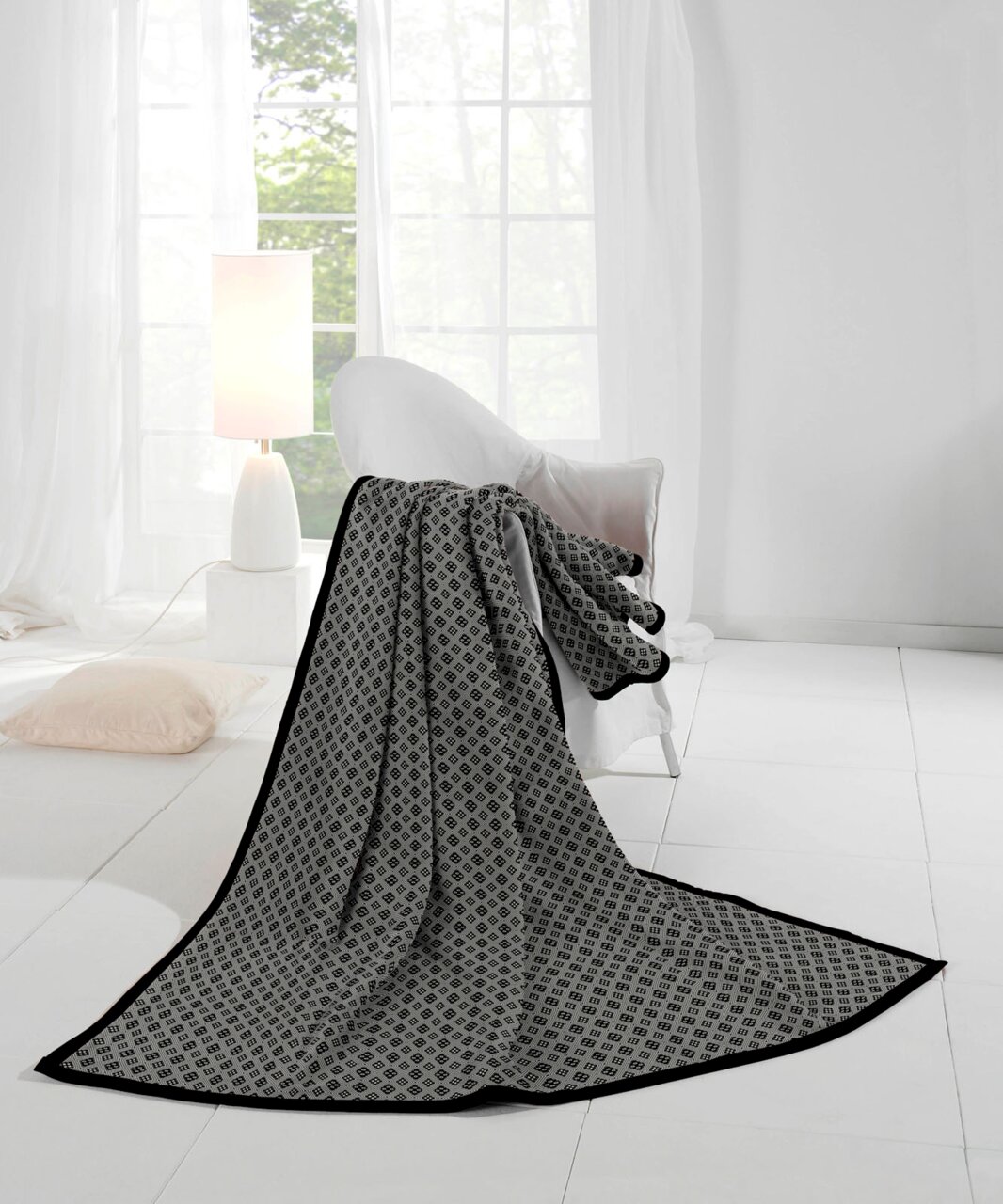 Elegante Wohndecke mit geometrischem Muster in einem hellen, modernen Raum, drapiert über einem Sessel, mit Blick auf ein großes Fenster.