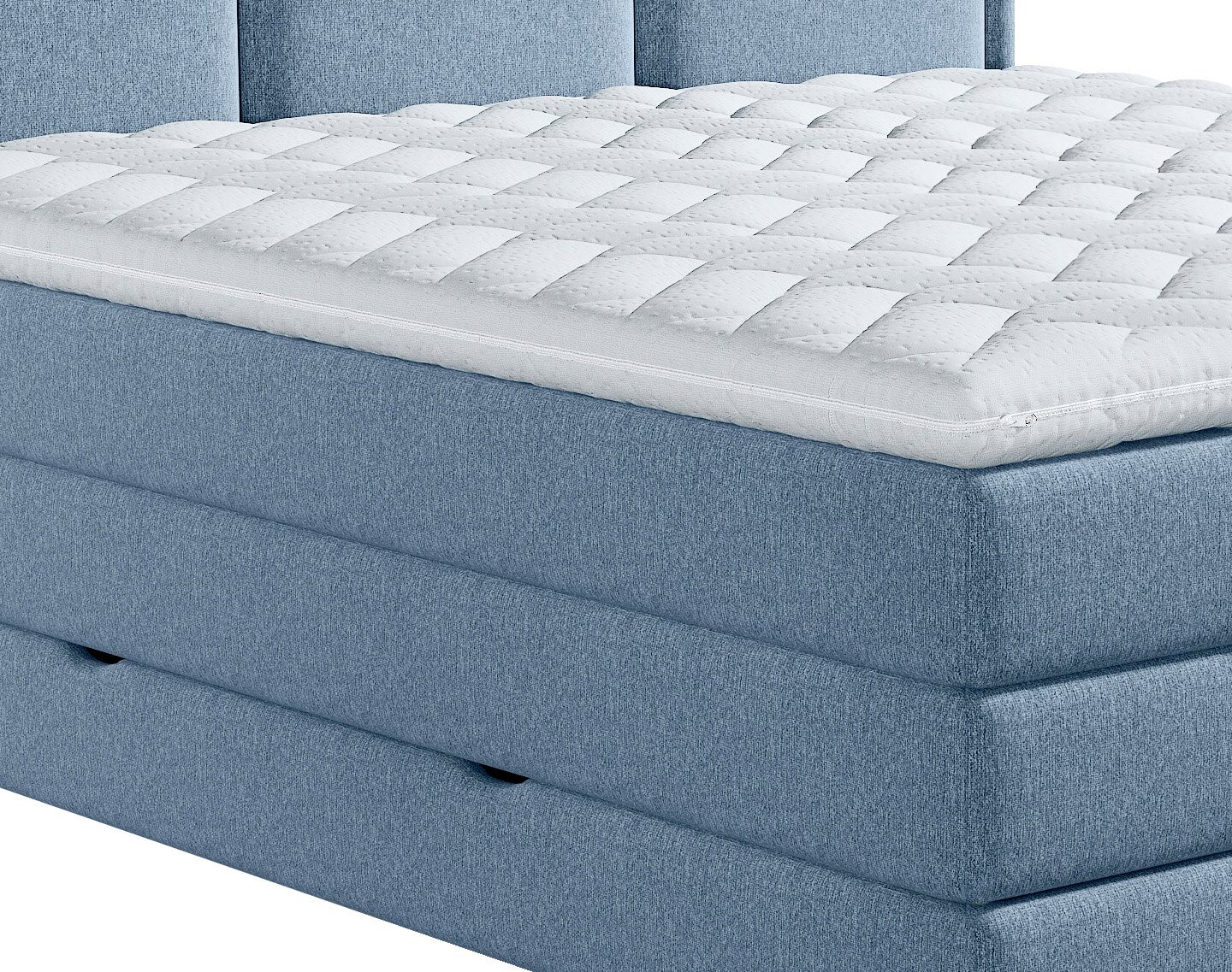 Close-up vanuit schuin vooraanzicht van een blauw gestoffeerd boxspringbed met een dikke, wit doorgestikte matrastopper.