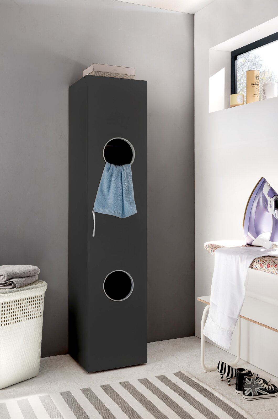 Moderne, smalle wasmand in een donkere kleur met ronde openingen, zijaanzicht