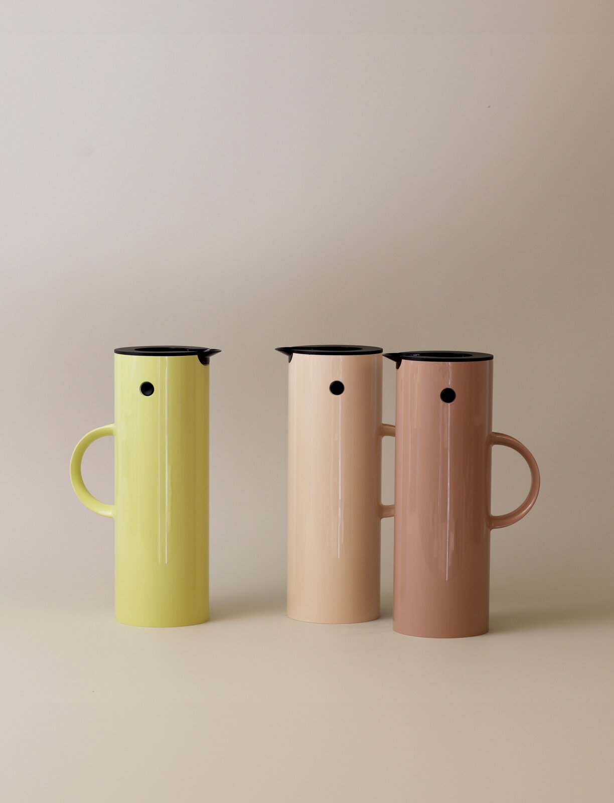 Drei EM77 Isolierkannen in verschiedenen Farben (Grün, Beige, Rosa) aus seitlicher Perspektive.