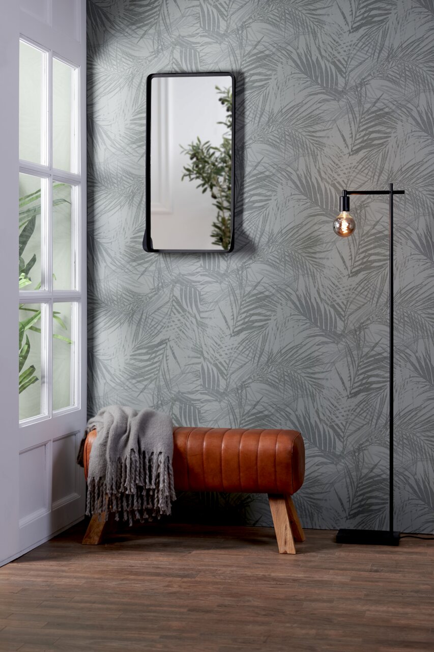 Bank aus braunem Leder mit Holzbeinen, seitliche Perspektive, dekoriert mit einer grauen Decke, vor einer Wand mit Pflanzenmuster.