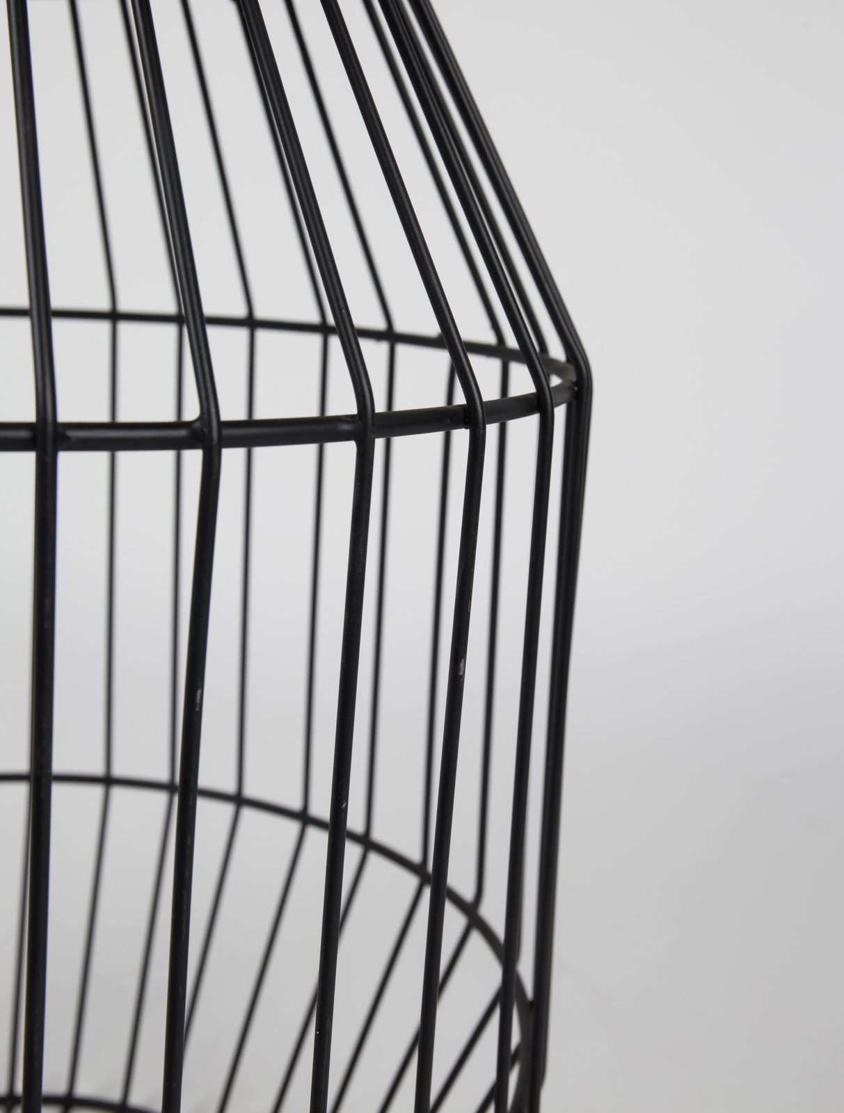 Nahaufnahme eines schwarzen, gitterförmigen Beistelltisches aus Metall, seitliche Perspektive