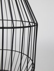 Nahaufnahme eines schwarzen, gitterförmigen Beistelltisches aus Metall, seitliche Perspektive