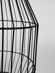 Nahaufnahme eines schwarzen, gitterförmigen Beistelltisches aus Metall, seitliche Perspektive