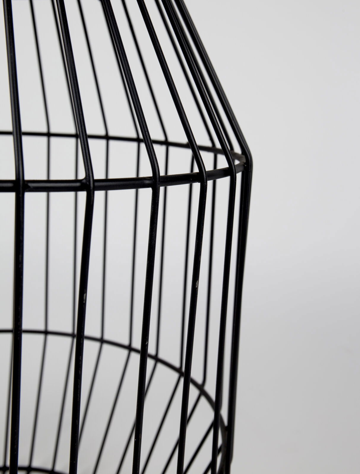 Nahaufnahme eines schwarzen, gitterförmigen Beistelltisches aus Metall, seitliche Perspektive