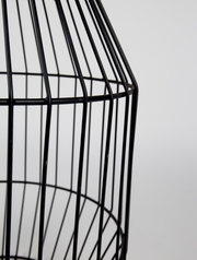 Nahaufnahme eines schwarzen, gitterförmigen Beistelltisches aus Metall, seitliche Perspektive