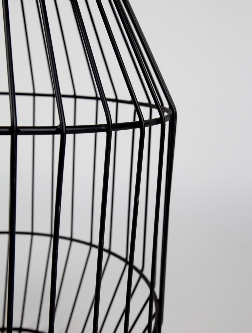 Close-up van een zwart, roostervormig bijzettafeltje van metaal, gezien vanaf de zijkant