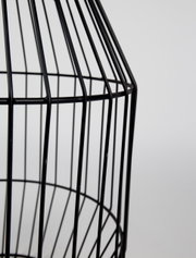 Close-up van een zwart, roostervormig bijzettafeltje van metaal, gezien vanaf de zijkant