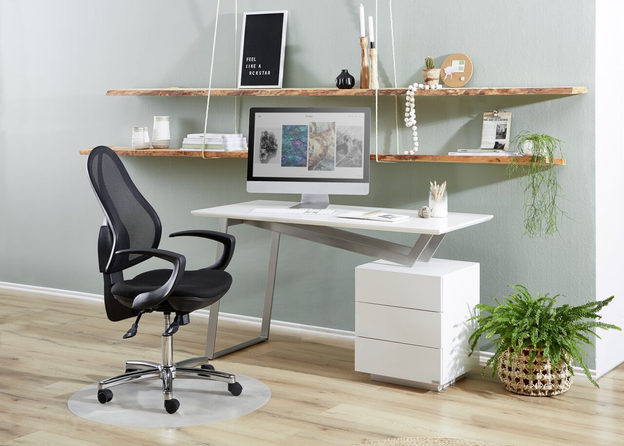 Novel Schreibtisch ERIC Moderner Schreibtisch mit weißer Tischplatte und silbernen Beinen, ausgestattet mit einem Computerbildschirm, umgeben von stilvollen Regalen und einem ergonomischen Bürostuhl, seitliche Perspektive.