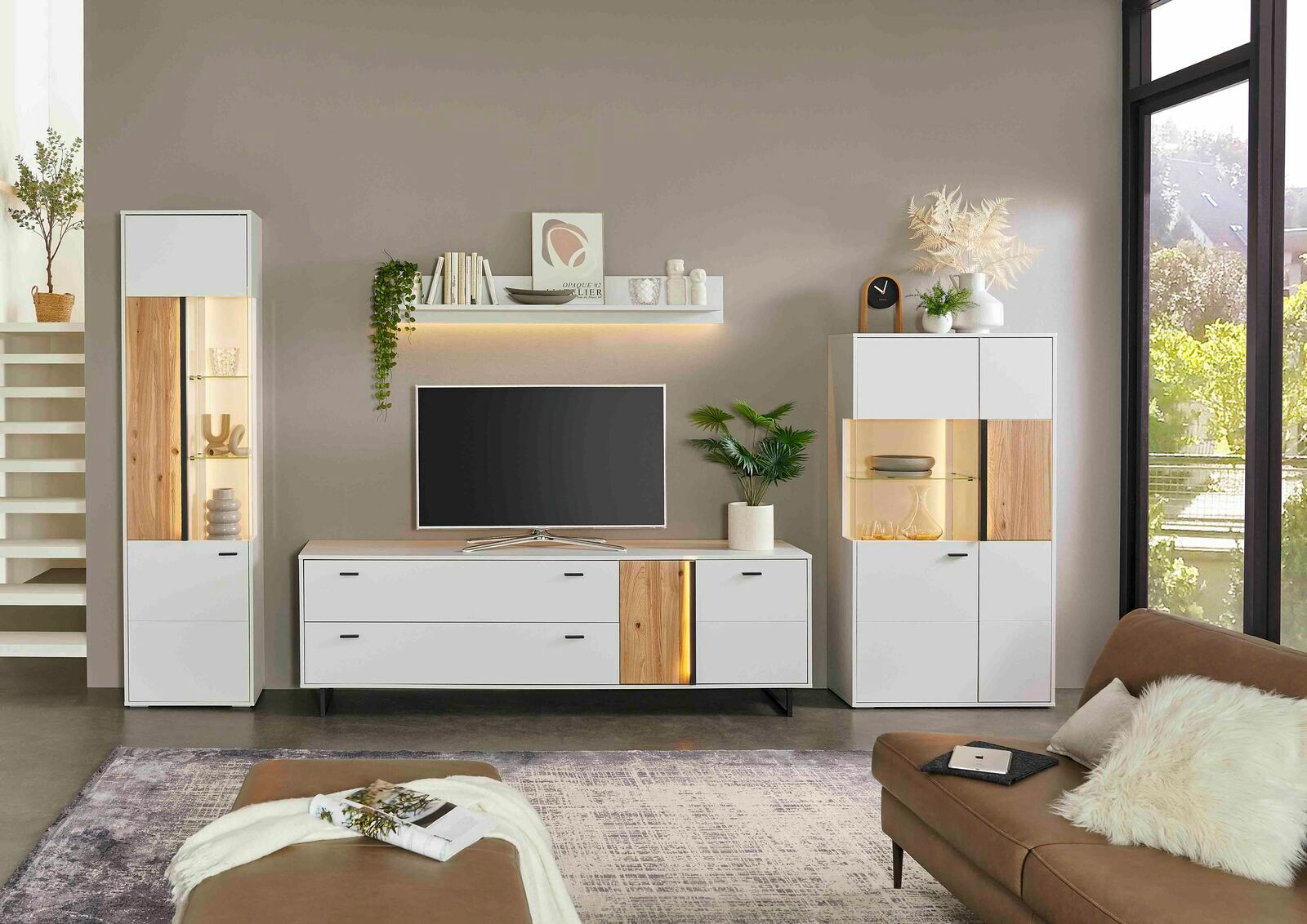Moderne Wohnzimmer-Vitrine in Weiß mit Holzelementen, links im Bild, frontal betrachtet.