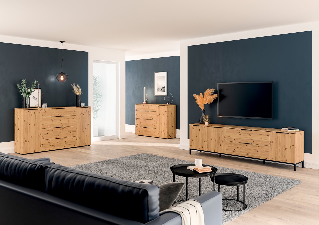 Wohnzimmer mit modernen Holzmöbeln, darunter ein XL TV-Lowboard und Sideboards, aus der Perspektive eines Sofas betrachtet.