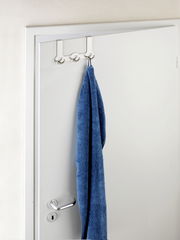Edelstahl Türgarderobe Rondo mit drei Haken, von vorne betrachtet, an einer weißen Tür mit einem blauen Handtuch.