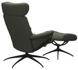 Rückansicht eines grünen Einzelsessels mit Kopfstütze und passendem Fußhocker auf schwarzem Drehgestell.