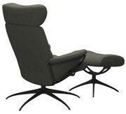 Rückansicht eines grünen Einzelsessels mit Kopfstütze und passendem Fußhocker auf schwarzem Drehgestell.