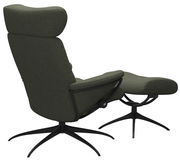 Rückansicht eines grünen Einzelsessels mit Kopfstütze und passendem Fußhocker auf schwarzem Drehgestell.