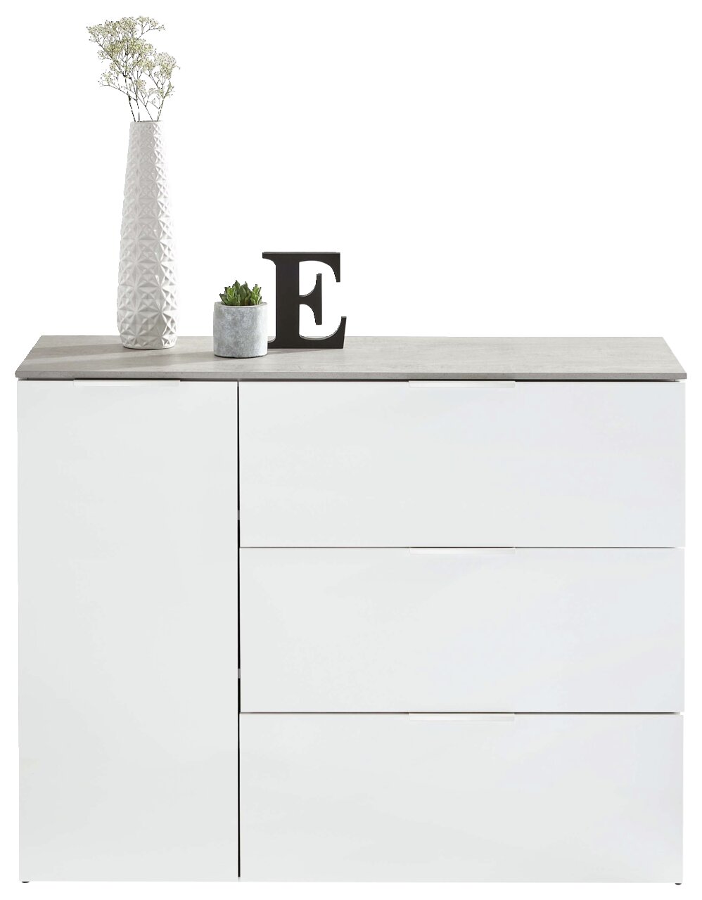 Modern wit dressoir met drie lades en een deur, versierd met een hoge vaas, een klein plantje en een letter E, gezien vanaf de voorkant.