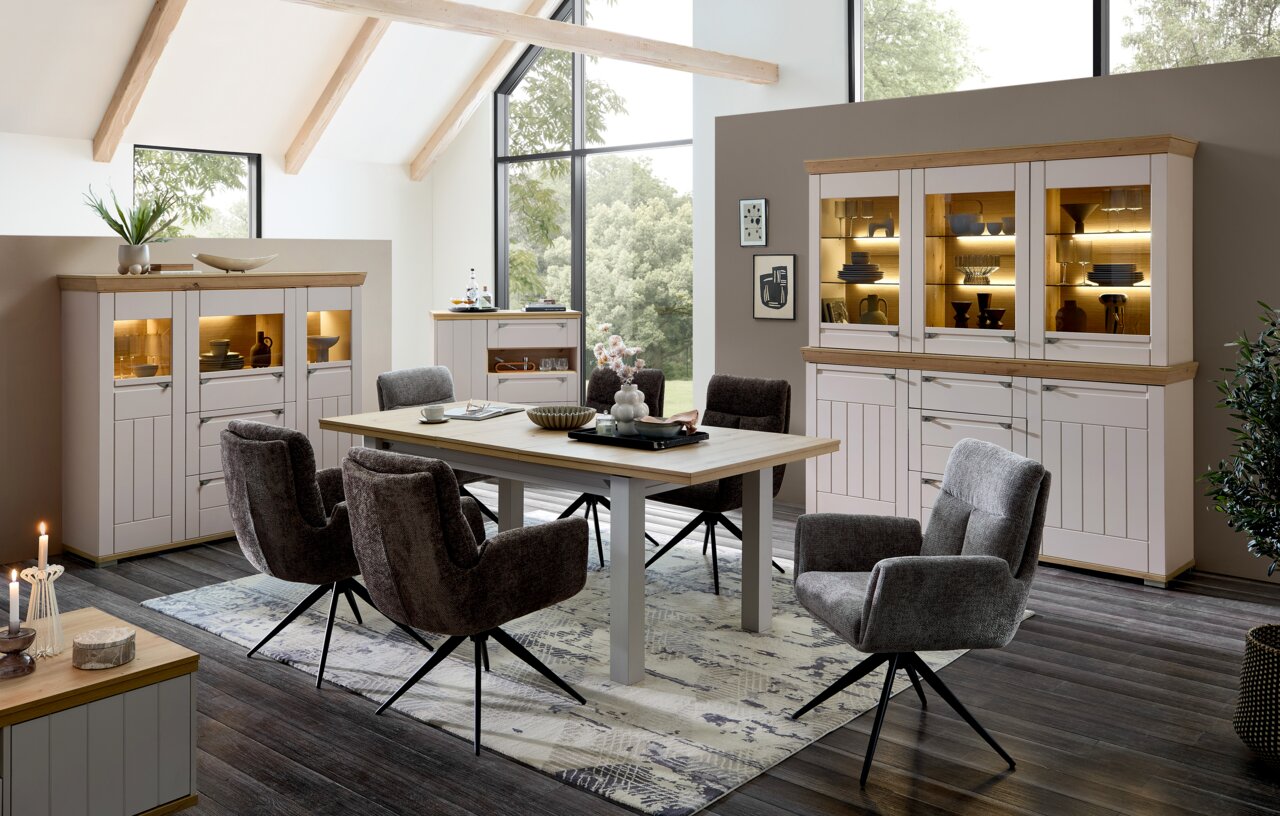 Esszimmer mit modernem Design, bestehend aus einem großen Holztisch und sechs gepolsterten Stühlen mit schwarzem Metallgestell, in einem hellen Raum mit großen Fenstern und stilvollen Vitrinen. Perspektive: seitlich.