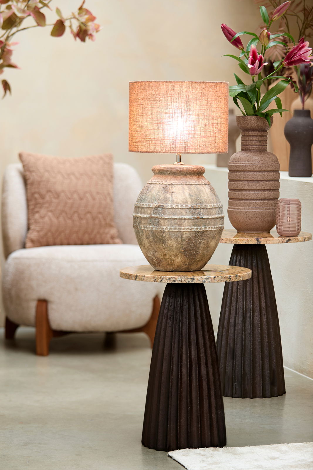 Rustikaler Lampenschirm auf antikem Keramikfuß, seitliche Perspektive, umgeben von moderner Einrichtung und Blumen.